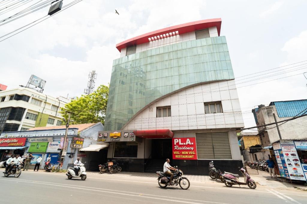 a building on the side of a street with people riding motorcycles at PLA Residency Tanjore in Thanjāvūr
