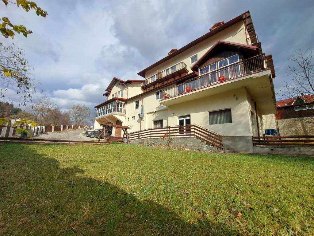 a large house with a grass field in front of it at Paradis in Buşteni