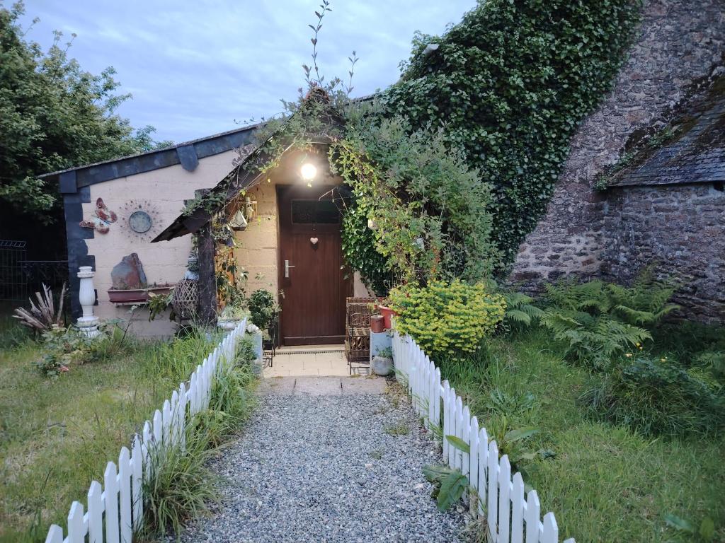 a small house with a wooden door and a fence at Namaste Gîte in Plounevez-Quintin