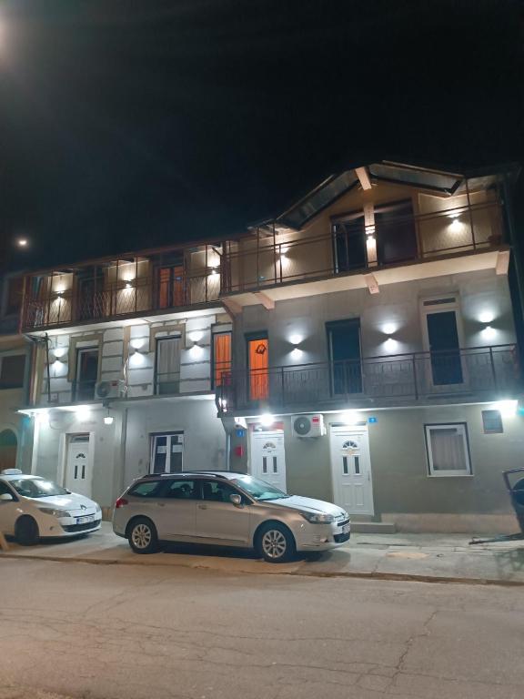 two cars parked in front of a building at night at Apartman Radoman in Cetinje