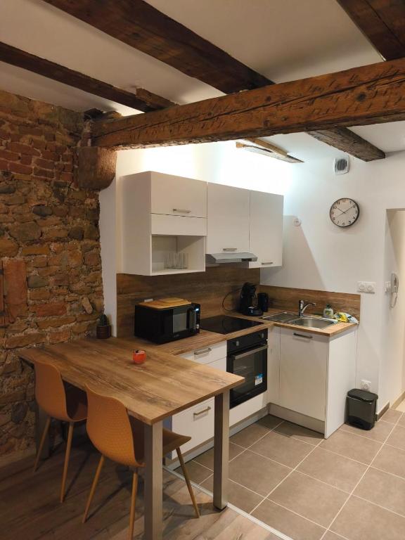 a kitchen with a wooden table and white cabinets at Logis Saint Martin in Colmar