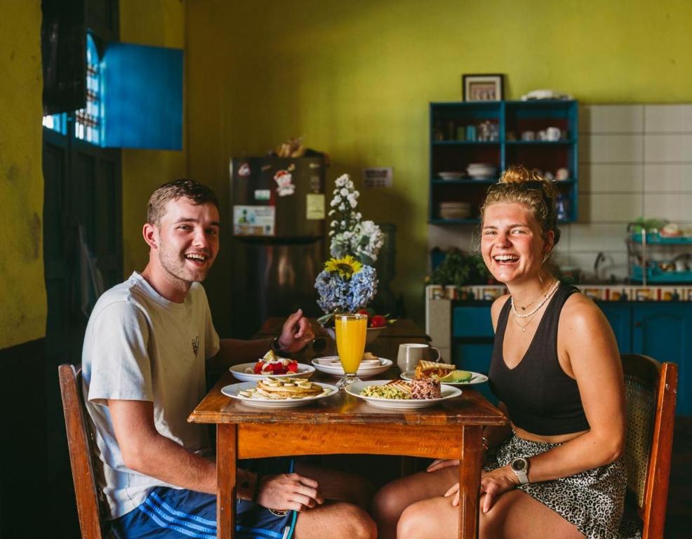 a man and a woman sitting at a table with food at Hostal Vacaciones Nicas in León