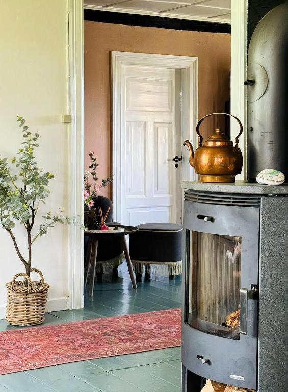 a kitchen with a tea kettle on top of an oven at Autentisk Gård Tæt På Vandet På Samsø in Ballen