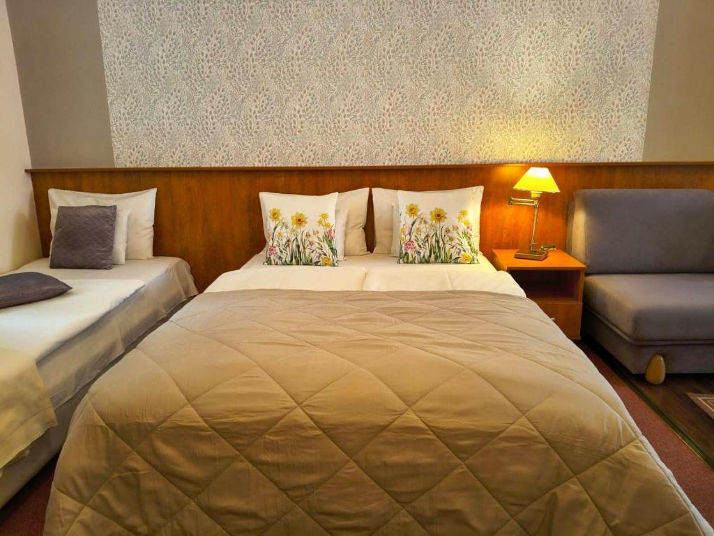 a bedroom with two beds and a couch and a chair at Hotel Isabell Győr in Győr
