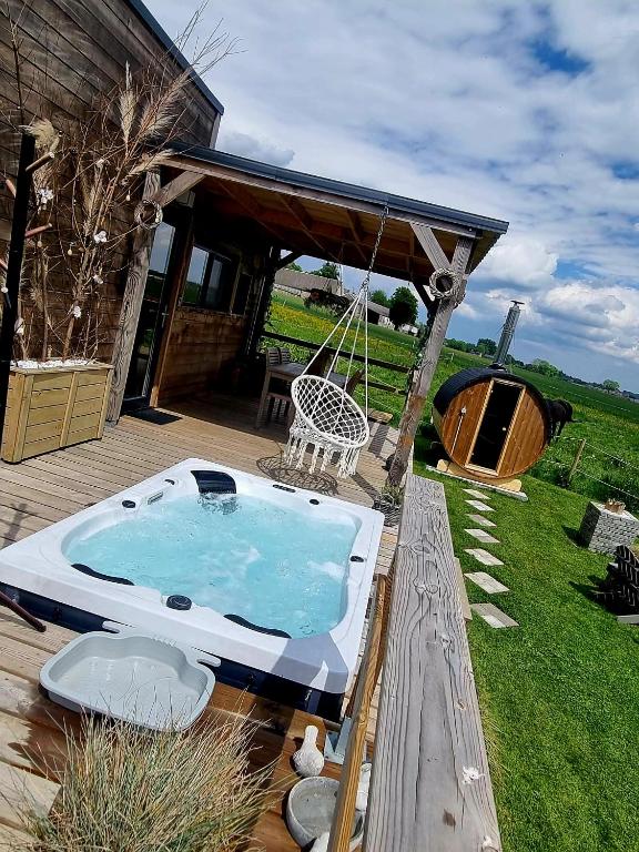 a hot tub sitting on a deck next to a house at Tiny housse serenity avec jacuzzi et piscine in Tinlot