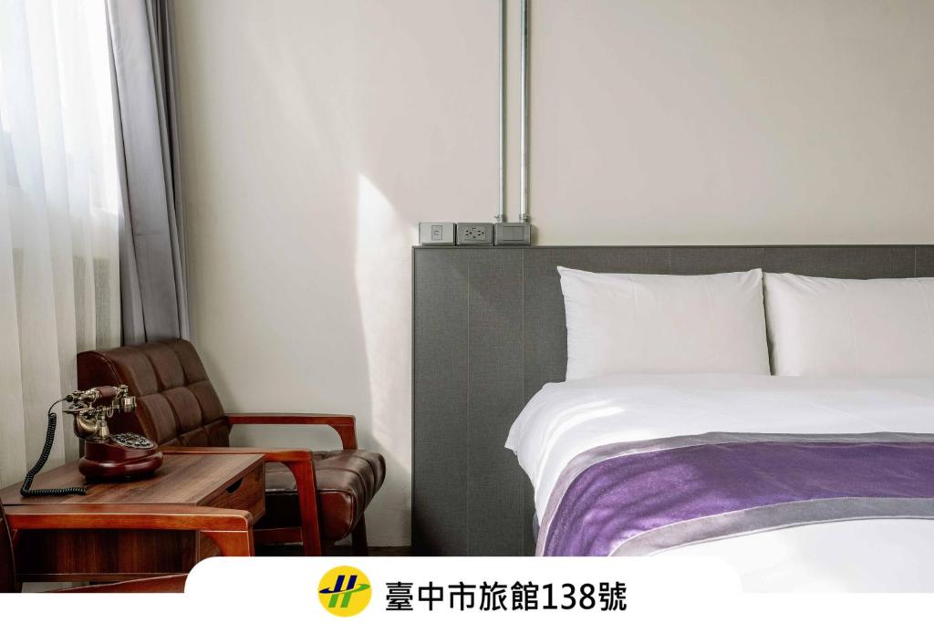 a bedroom with a bed and a table and a chair at Saturn Hotel in Taichung