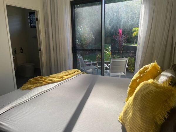 a bed with a yellow blanket on it in a bedroom at Eden on Beach in Palm Cove