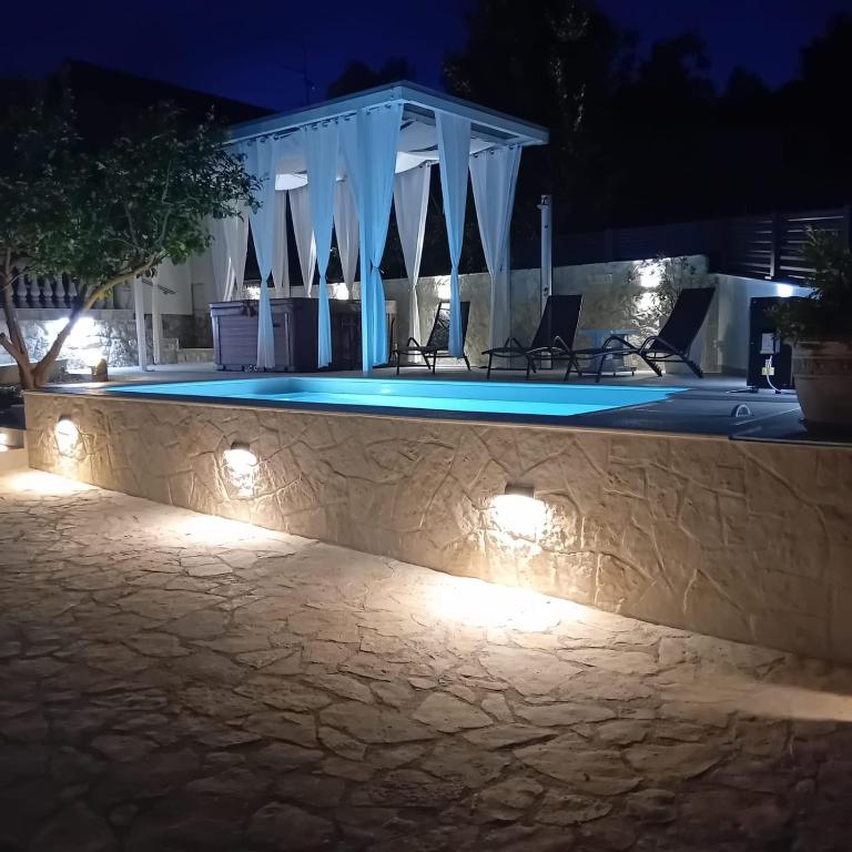 a swimming pool at night with lights on a wall at Villa Roko - Luxury Villa 60m from beach! in Ždrelac