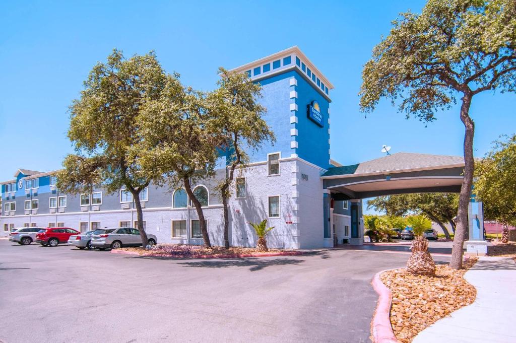 a building with a parking lot in front of it at Days Inn & Suites by Wyndham San Antonio North/Stone Oak in San Antonio