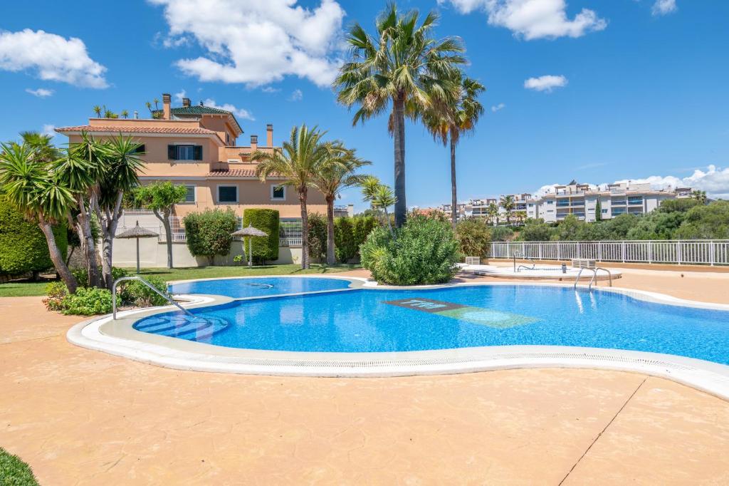 a swimming pool with palm trees in front of a house at Can Tomeu in Calas de Mallorca