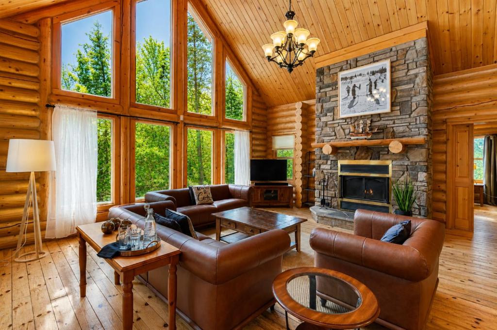 a living room with leather furniture and a stone fireplace at Fiddler Lake Resort - Deer 79 in Mille-Isles