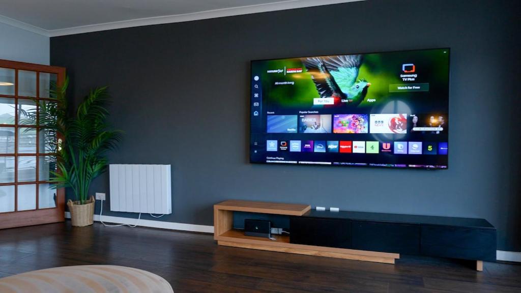 a living room with a large flat screen tv on a wall at Seaside Penthouse 1 in Largs