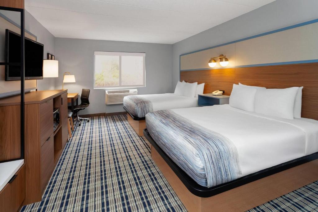 a hotel room with two beds and a flat screen tv at AmericInn by Wyndham Appleton North Little Chute in Appleton