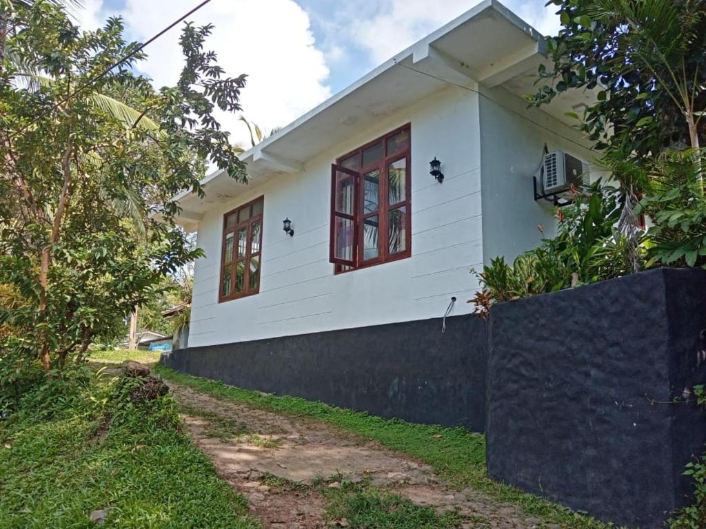 a white house with red windows and a fence at Mariya Villa in Unawatuna