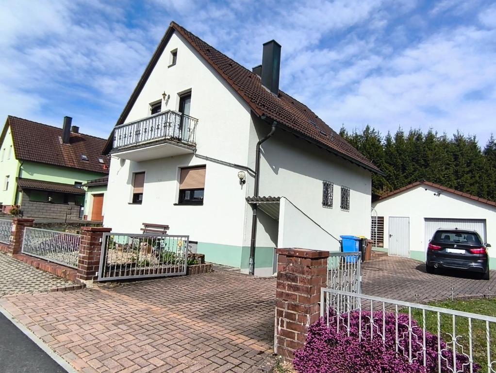 a white house with a balcony on a brick driveway at FeWo Rina in Pottenstein