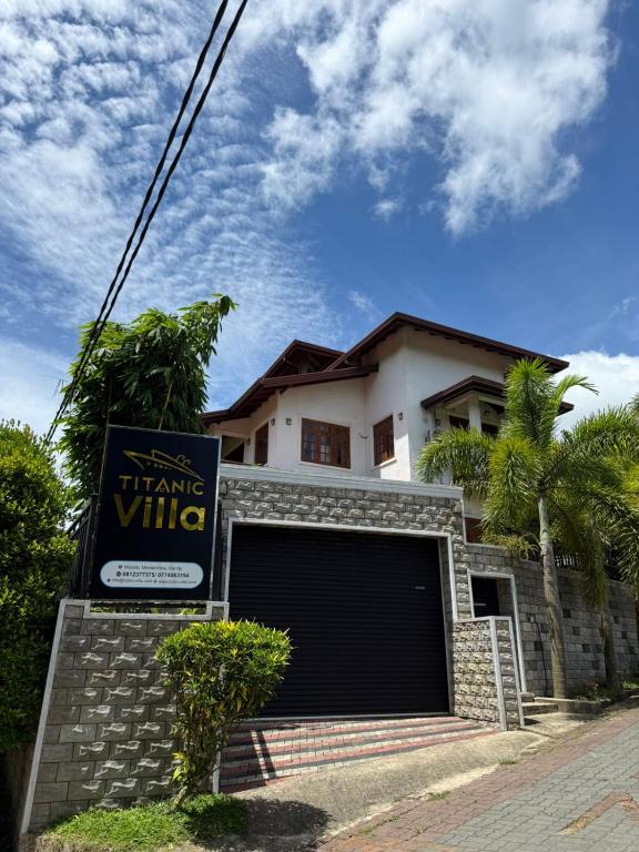 a house with a garage with a sign in front of it at Titanic Villa Kandy in Kandy