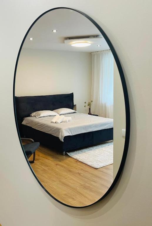 a mirror reflecting a bed in a bedroom at S&A2 apartamentai in Panevėžys