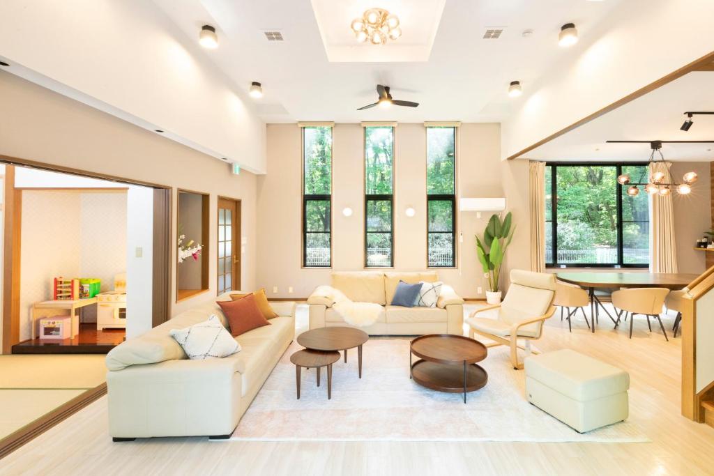 a living room with white furniture and a table at HARMONIA 那須 Nas-MAX26名-川遊び-BBQ-カラオケのできる宿 in Nasu