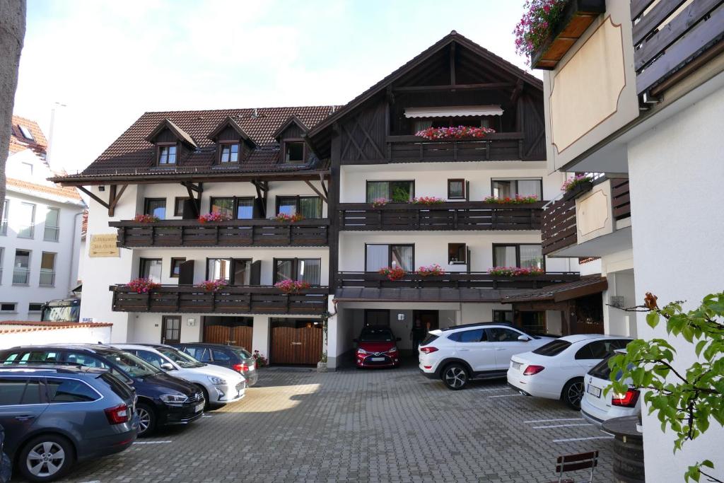 a large building with cars parked in a parking lot at Altstadthotel "Zum Hechten" in Füssen