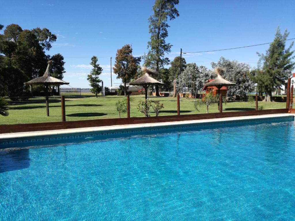 una gran piscina con sombrillas y un campo en Náutico Apart Hotel en Chascomús