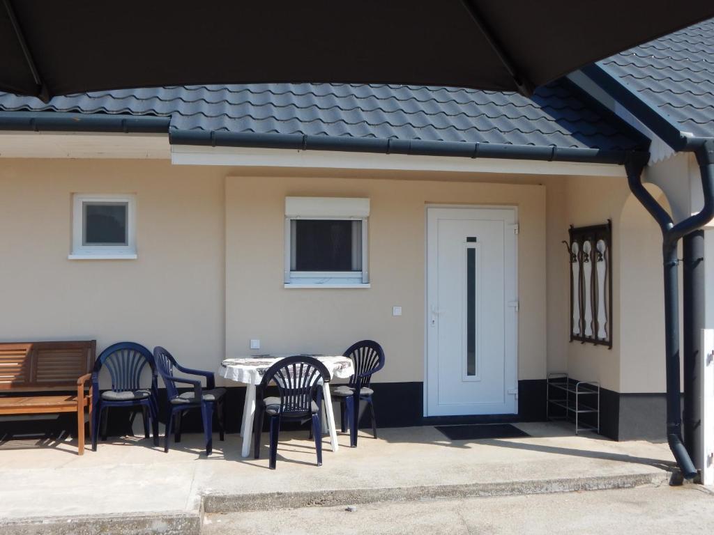 a patio with a table and chairs and a white house at JundJ Ferienwohnungen in Buzsák