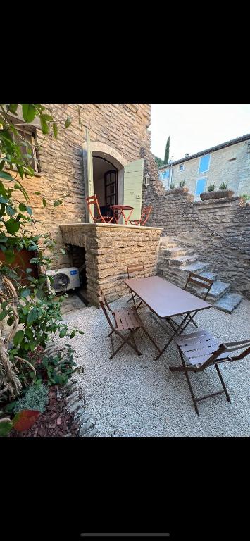 a table and two chairs in front of a brick wall at Authentic village house in Goult