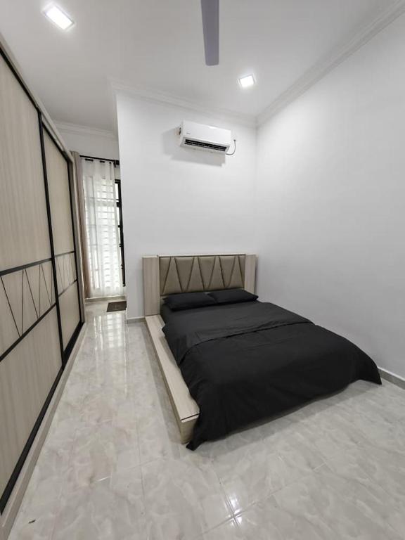 a bedroom with a black bed in a white room at UMRA Homestay in Kampong Padang Kemunting