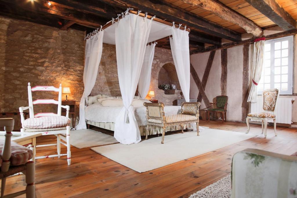 - une chambre avec un lit à baldaquin et des chaises dans l'établissement Villa La Roseraie avec accès piscine Hôtel La Roseraie, à Montignac