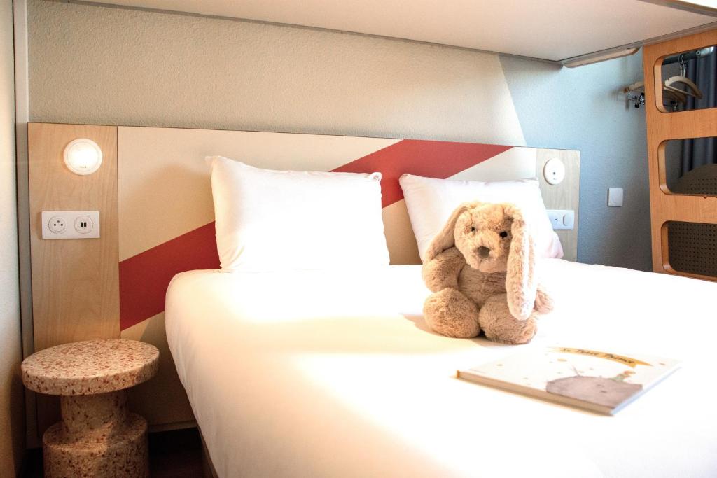 a teddy bear sitting on a bed in a room at ibis budget Bordeaux Sud in Villenave-dʼOrnon