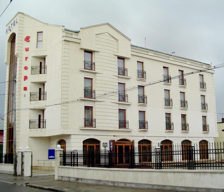 a white building with a fence in front of it at Hotel Europa in Ploieşti