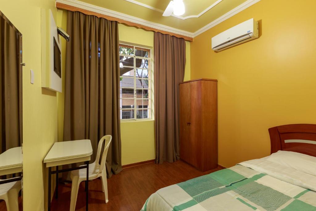 a bedroom with a bed and a table and a desk at Hotel Boa Viagem in Belo Horizonte