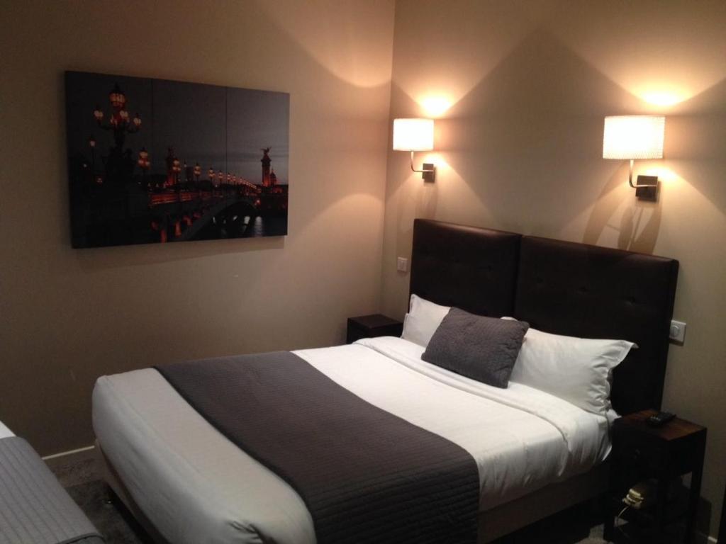 Ce lit se trouve dans une chambre d'hôtel dotée de 2 lampes murales. dans l'établissement Hotel Cosy Monceau, à Paris