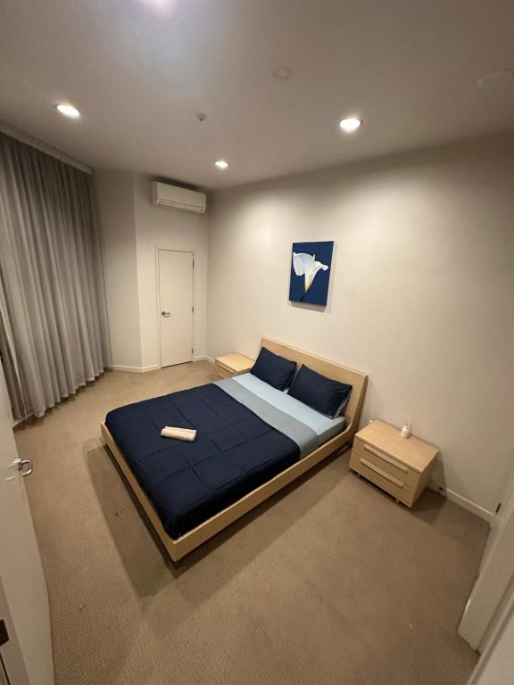 a bedroom with a large bed with blue sheets and blue pillows at Viaduct Spacious 2 Bedroom Apartment in Auckland