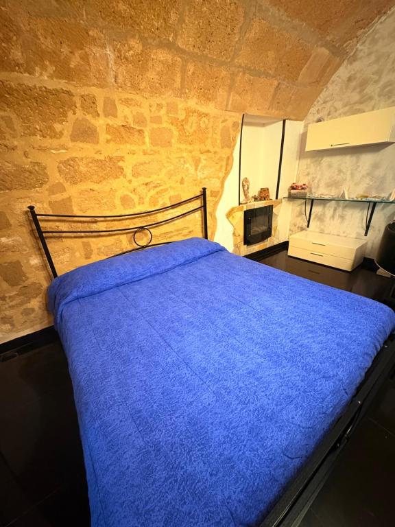 ein Schlafzimmer mit einem blauen Bett in einer Steinmauer in der Unterkunft Lu bobò in Alghero