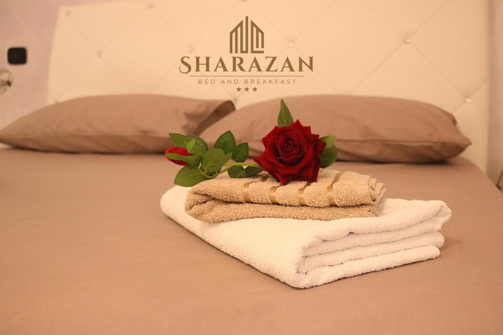 a pile of towels and a rose on a bed at Sharazan in Canicattì