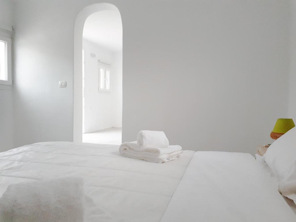 a white bedroom with a bed with towels on it at Almond Deluxe Suite in Santorini