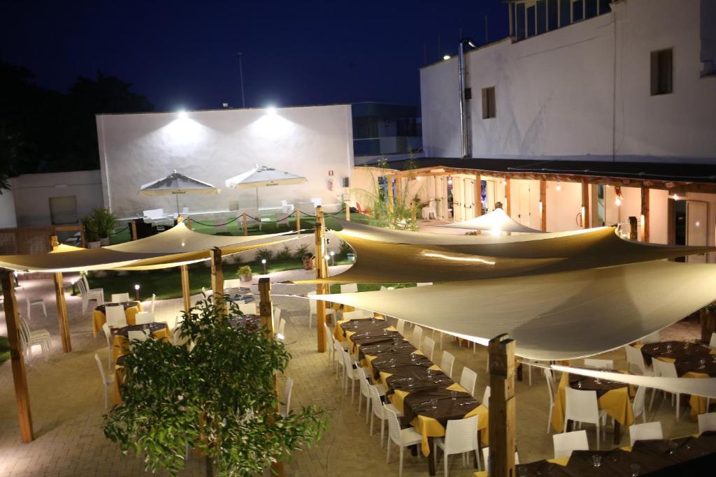 a group of tables and umbrellas on a patio at night at Pensione Solaris in Torre Lapillo