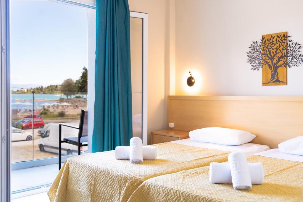a hotel room with two beds and a balcony at Penelope - Sea Front Studio in Gouvia