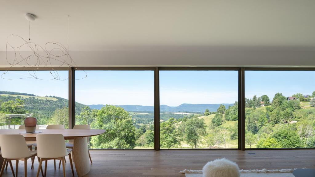 a dining room with a table and a large window at Chalet DU MERLE - CHAMP DU FEU - NEUF 5 ETOILES in Belmont
