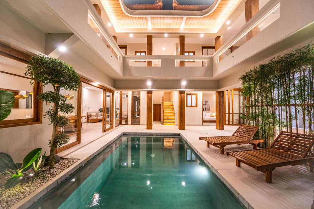 an indoor pool in a house with two chairs at Villa Ume Seseh in Munggu
