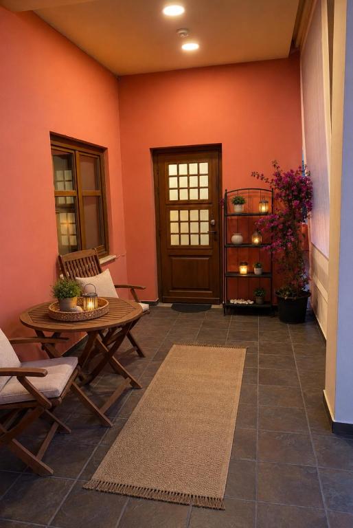 a living room with orange walls and a table and chairs at Casa Polyxeni -Elegant Stay in Vathi in Samos