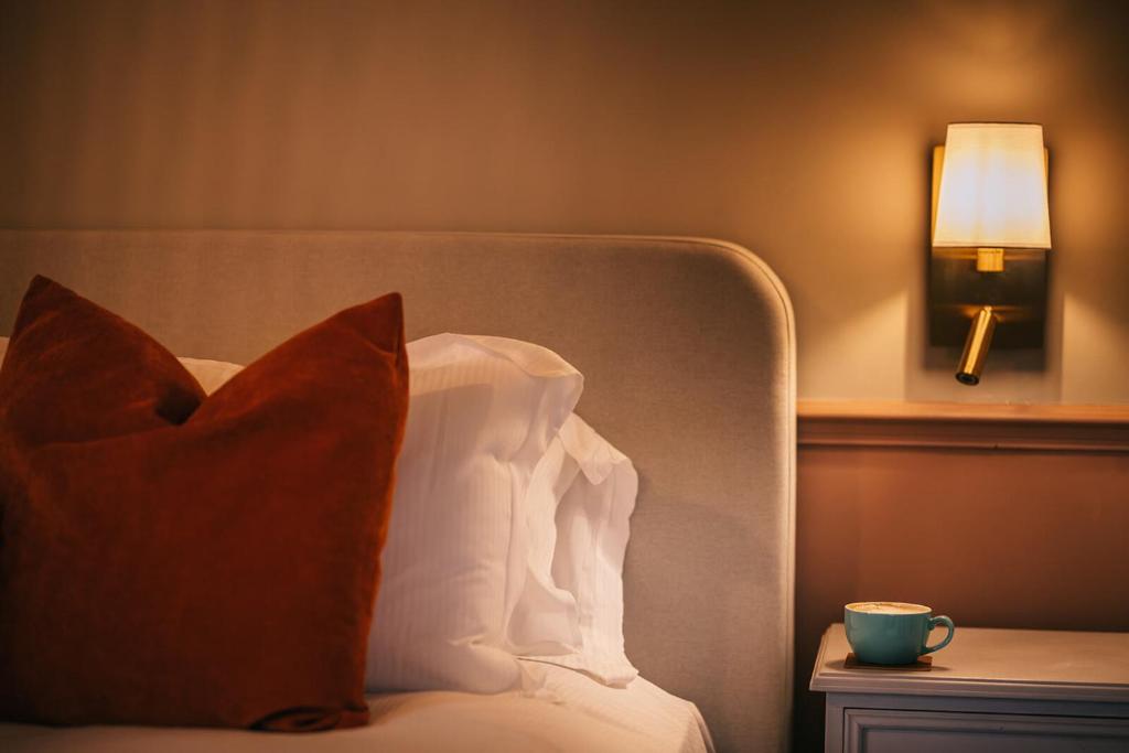 a bed with a pillow and a cup on a table at Boot & Shoe in Flintham