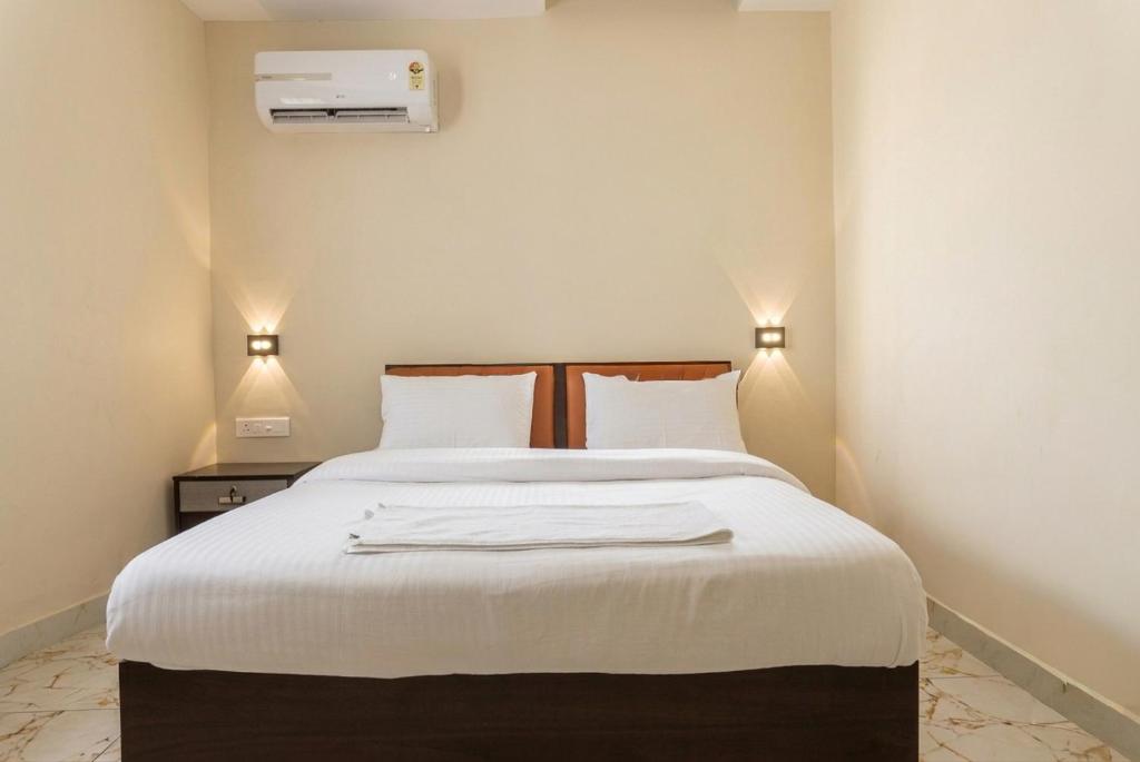 a bedroom with a large bed with white sheets at Hotel Vista by Booksy One Kollam Near Kollam Bypass in Kollam