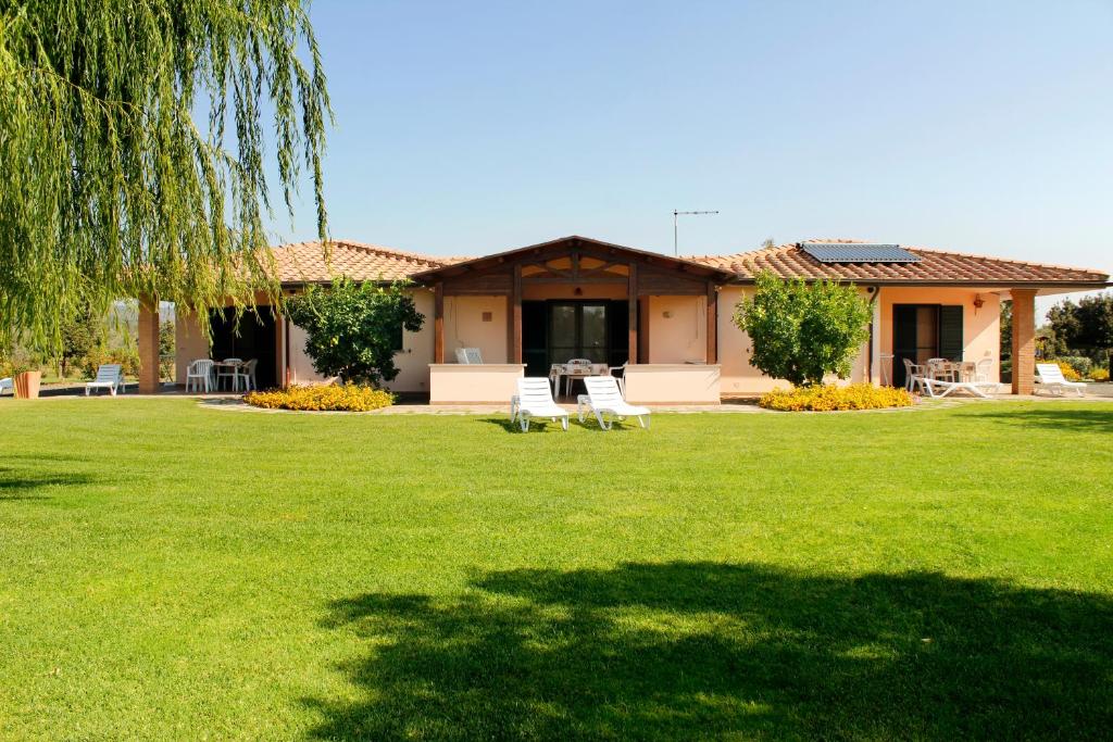 une maison avec une pelouse verte devant elle dans l'établissement Agriturismo Bocci, à Castiglione della Pescaia