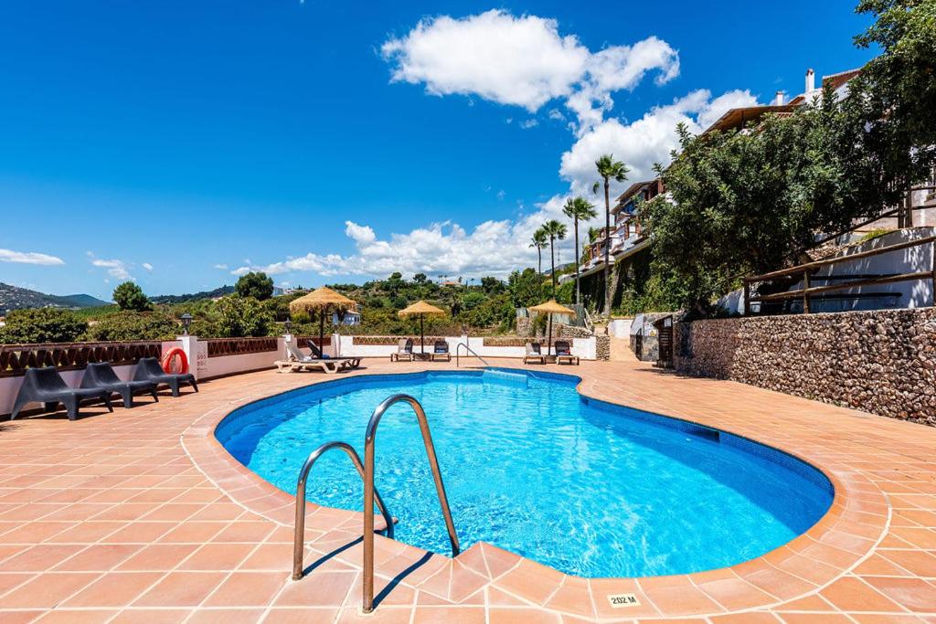 a swimming pool in a resort with tables and chairs at Hotel Rural Almazara in Frigiliana