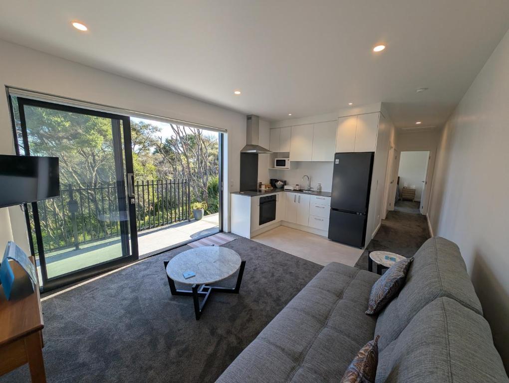 a living room with a couch and a kitchen at Gumlands Retreat in Auckland