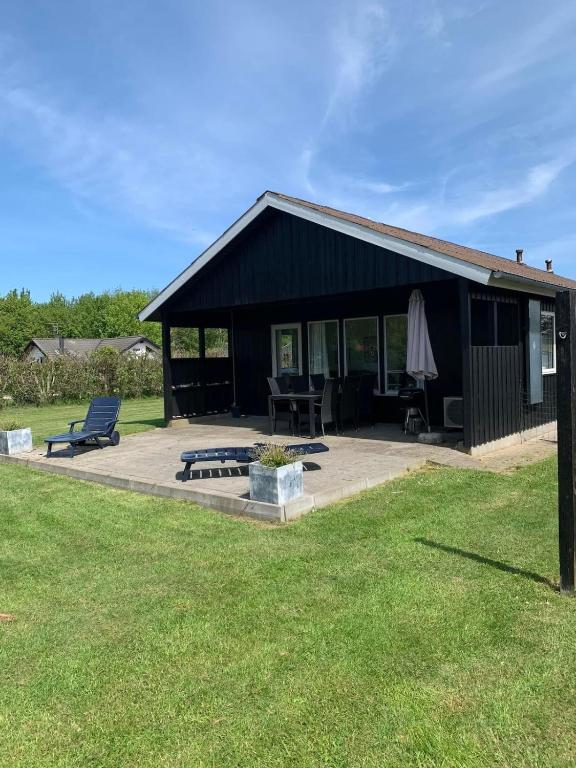 a black building with a picnic table and an umbrella at Beautiful bright summer cottage in Skovbyballe