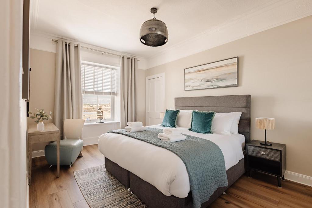 a bedroom with a large bed with blue pillows at At Anchor (with a Harbour View) in Fife