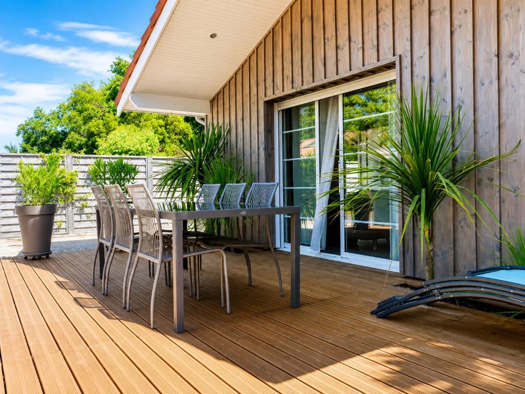 a wooden deck with a table and chairs on it at Chalet Familial 6 personnes in Gujan-Mestras
