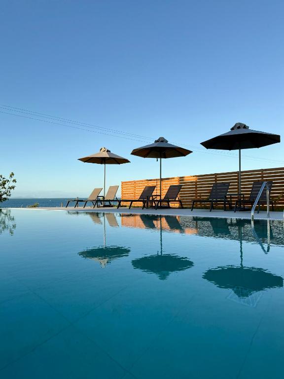 a pool with chairs and umbrellas on the beach at Kyllini Seaside Apartments & Rooms in Kyllini